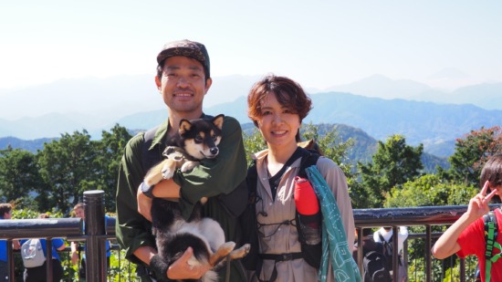 高尾山山頂で愛犬かなでを抱く小倉和也と小倉友香