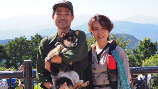 高尾山山頂で愛犬かなでを抱く小倉和也と小倉友香